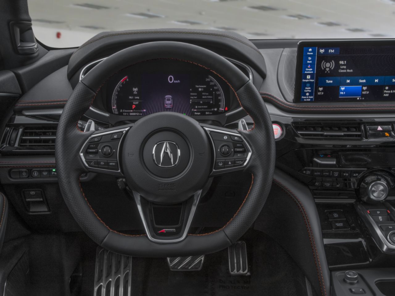 Habitacle d’un Acura MDX avec volant sport multifonction en cuir, tableau de bord numérique, écran tactile multimédia avec radio affichée et console centrale haut de gamme au design moderne.